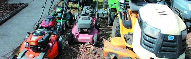 Lawn mowers and a lawn tractor lined up for service
